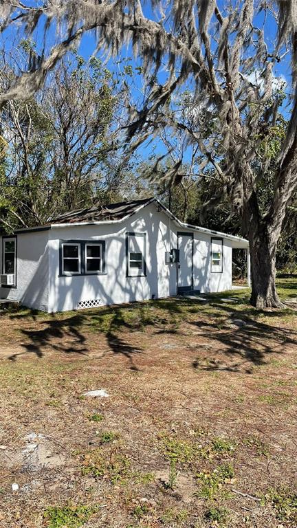 A white, single-story house with a gabled roof sits under trees draped in Spanish moss — 205 S GROVE STREET, EUSTIS, FL