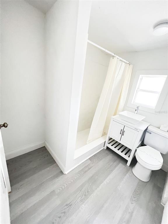 A bathroom features a shower stall, a white vanity with a vessel sink, and flooring — 205 S GROVE STREET, EUSTIS, FL