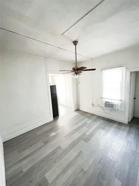 An interior room features light wood-look flooring, a ceiling fan, and a window air conditioner — 205 S GROVE STREET, EUSTIS, FL