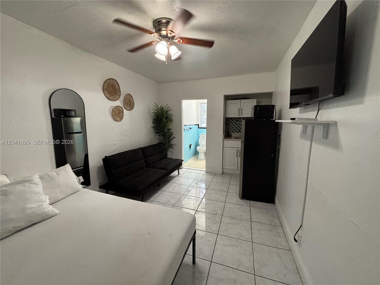 A studio apartment features a bed, sofa, kitchenette, and a bathroom with blue tile — 1843 Dewey St # 118, Hollywood FL 33020, HOLLYWOOD, FL
