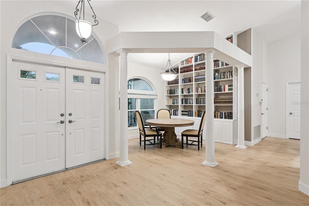A foyer features light wood flooring, a circular dining table, and built-in floor-to-ceiling bookshelves — 14962 FAVERSHAM CIRCLE, ORLANDO, FL