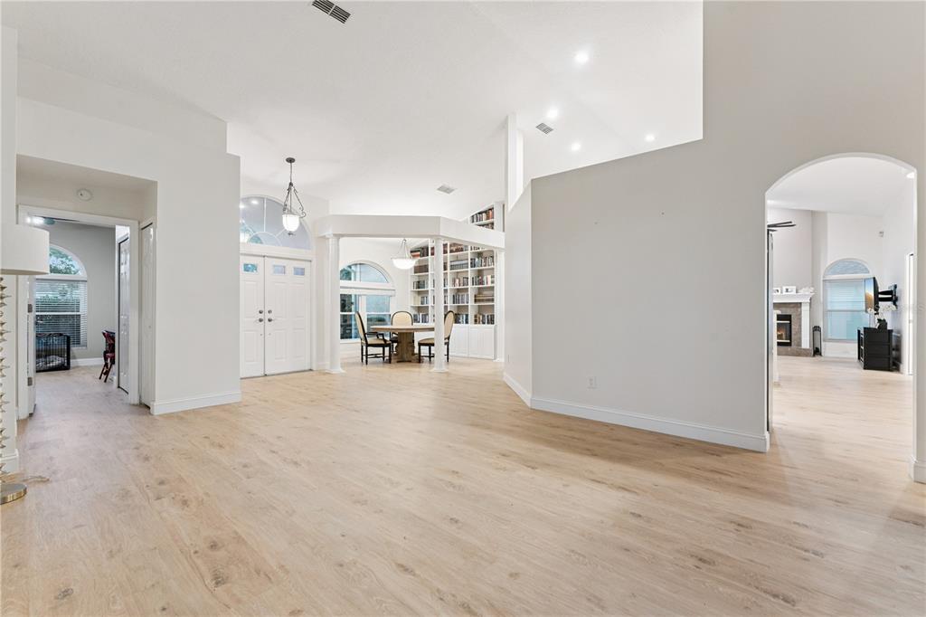 A spacious living area features light wood flooring, white walls, and a built-in bookshelf — 14962 FAVERSHAM CIRCLE, ORLANDO, FL