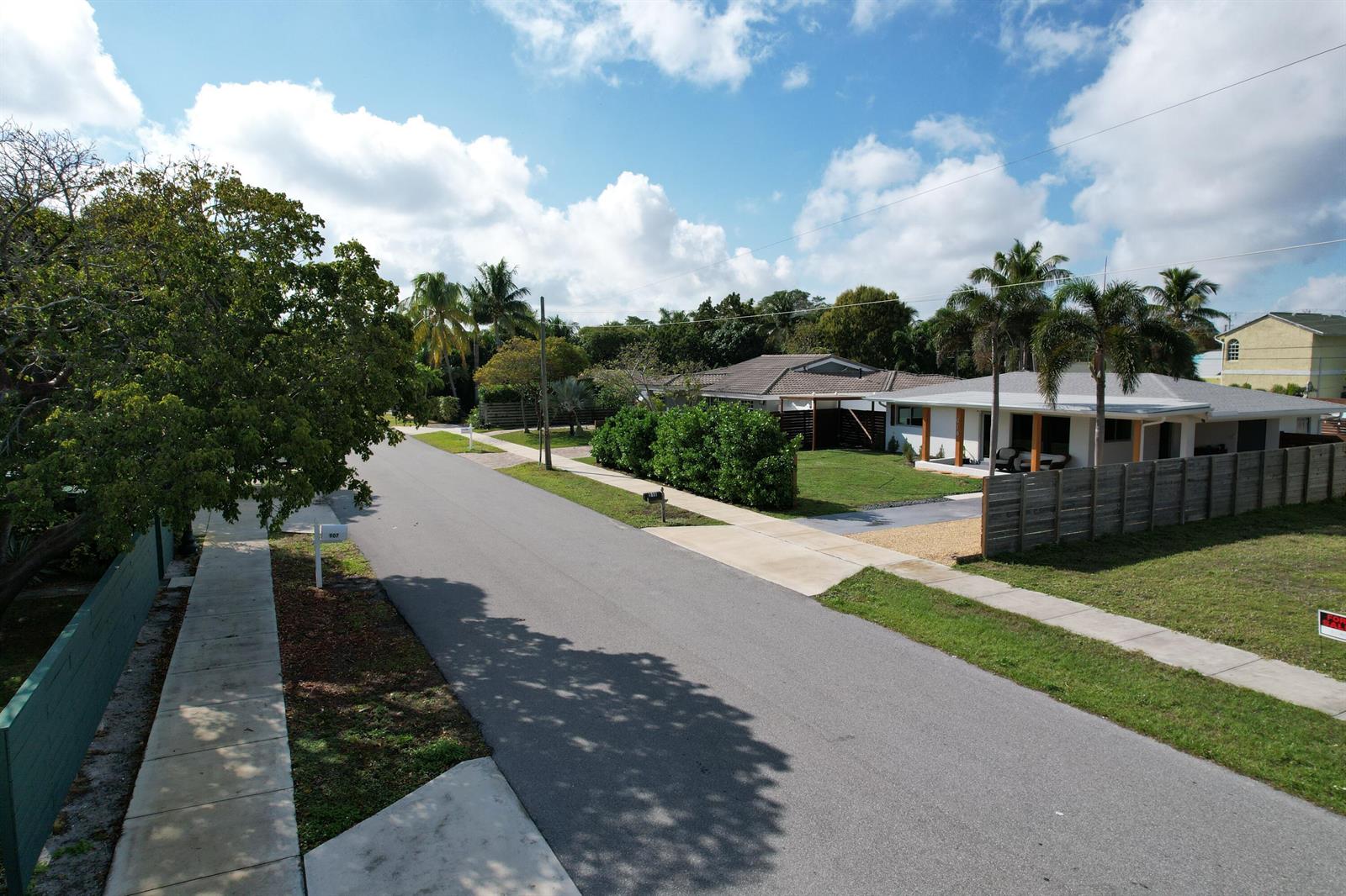 An elevated view of a suburban street featuring houses, palm trees, and a wooden fence — 910 SE 3rd Avenue, Delray Beach FL 33483, DELRAY BEACH, FL