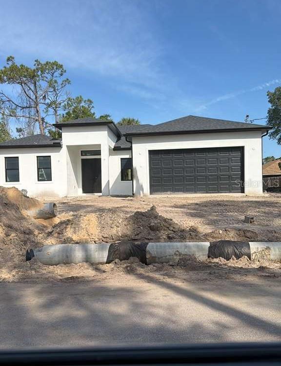 A modern white house with a black garage door and a small inset photo comparison — 3407 CULPEPPER TERRACE, NORTH PORT, FL