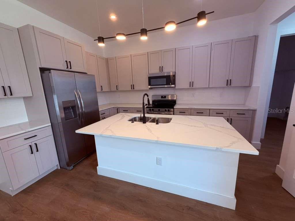 An open-concept living area features light wood flooring, recessed lighting, and a modern kitchen — 3407 CULPEPPER TERRACE, NORTH PORT, FL