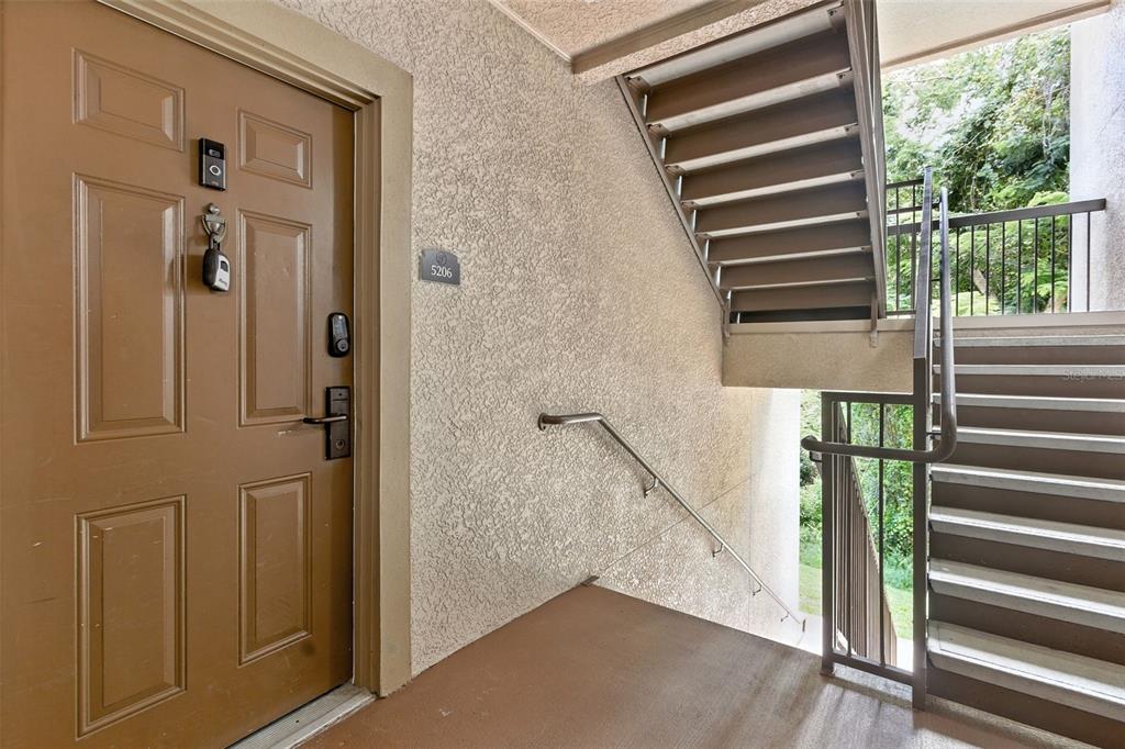 A brown apartment door with a keypad lock is next to an outdoor stairwell — 8010 TUSCANY WAY UNIT 5206, DAVENPORT, FL