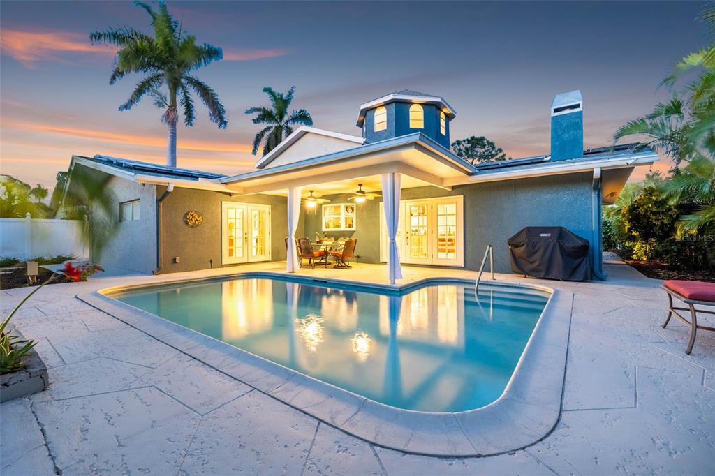 A backyard swimming pool sits in front of a house with a covered patio area — 342 2ND AVENUE N, TIERRA VERDE, FL