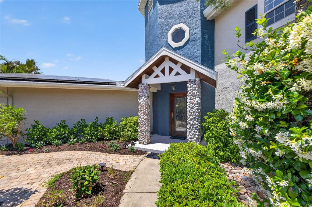 The exterior of a house features a stone-columned entryway and a blue stucco facade — 342 2ND AVENUE N, TIERRA VERDE, FL