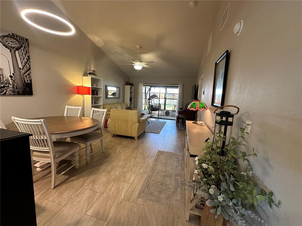 An open-concept living and dining area features tile flooring, a vaulted ceiling, and patio access — 5480 BRASSY LOOP, NORTH PORT, FL
