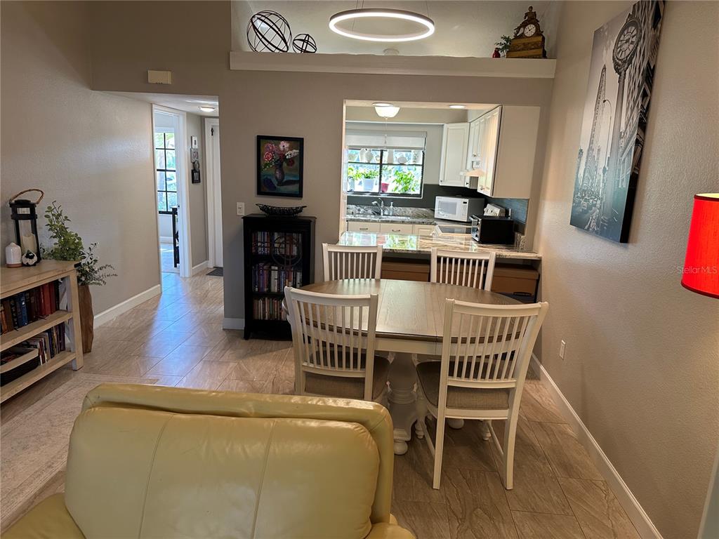 A dining area with a round table and chairs sits adjacent to an open kitchen — 5480 BRASSY LOOP, NORTH PORT, FL