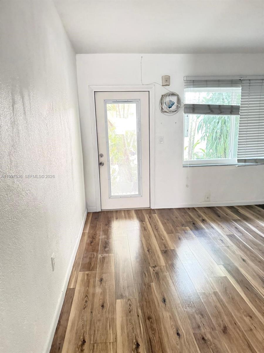 A room with wood-look flooring, a white door with a glass panel, and a window — 655 Meridian Ave # 2, Miami Beach FL 33139, MIAMI BEACH, FL