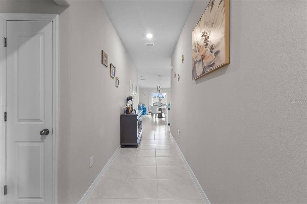 A long hallway with light tile flooring leads toward an open-concept dining area — 5426 BLUE AZURE DRIVE, WIMAUMA, FL