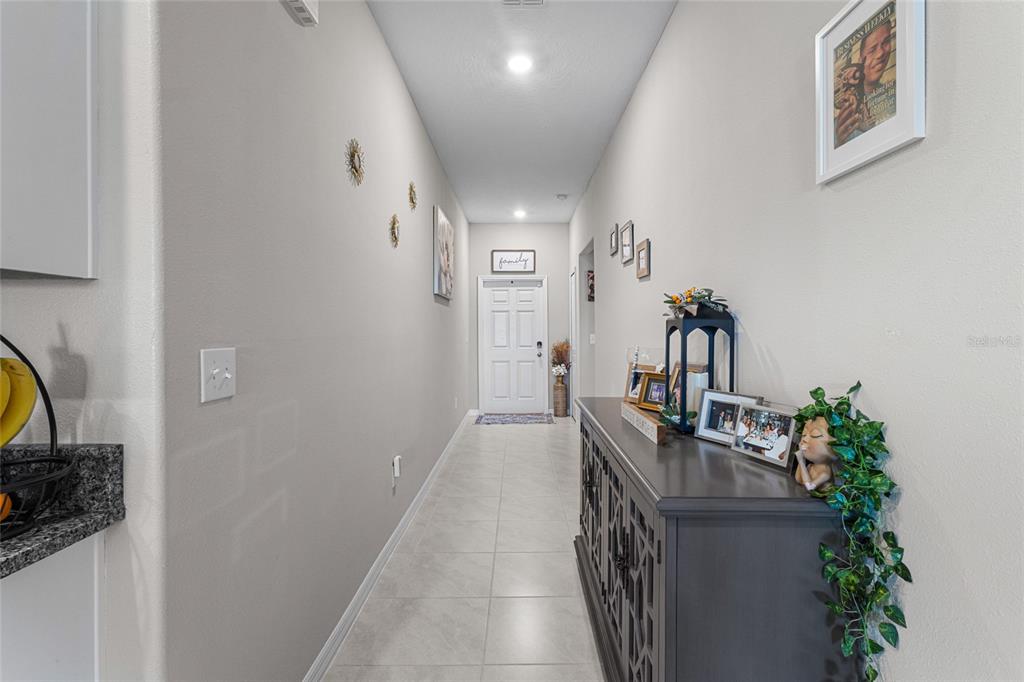 A hallway with light tile flooring leads to a white front door — 5426 BLUE AZURE DRIVE, WIMAUMA, FL