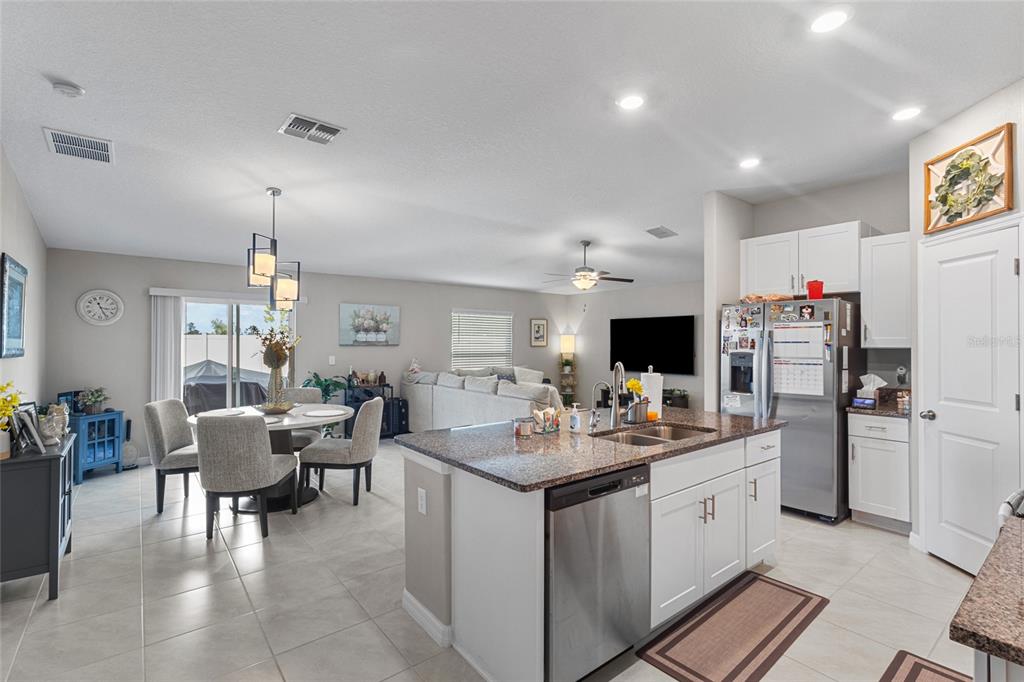 An open-concept kitchen with a granite island overlooks a dining area and living room — 5426 BLUE AZURE DRIVE, WIMAUMA, FL