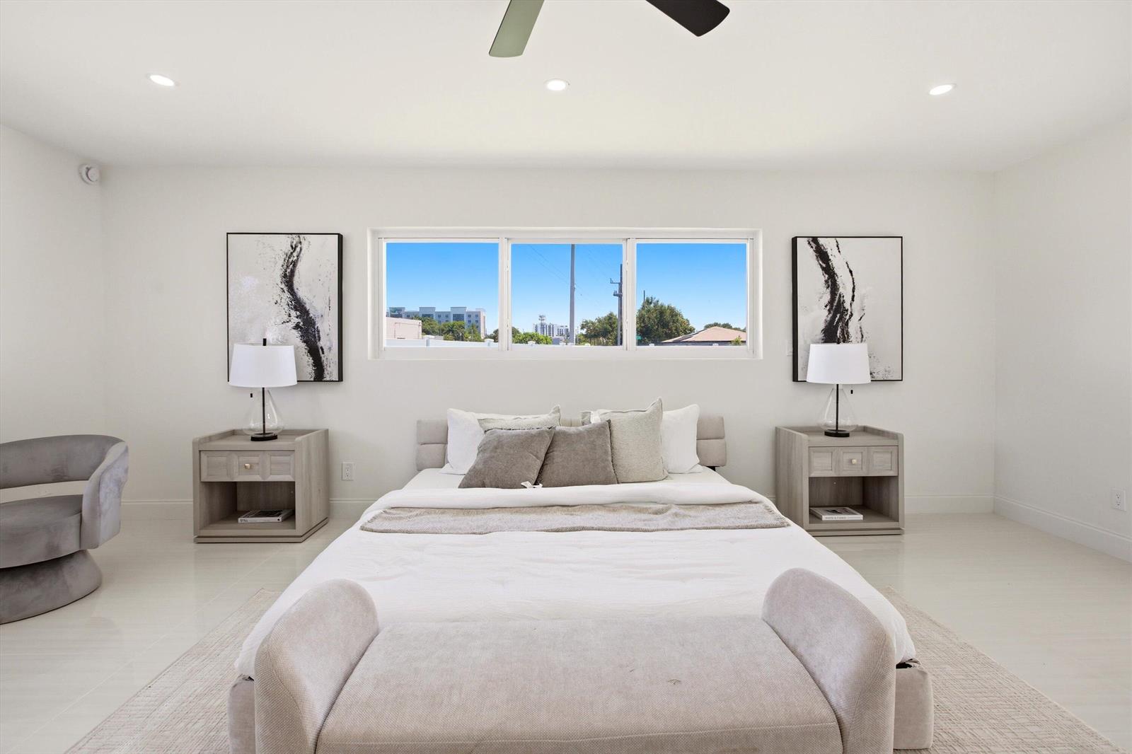 A bright, modern bedroom features a centered bed, two nightstands, and a large window — 401 NW 3rd Place, Dania Beach FL 33004, DANIA BEACH, FL