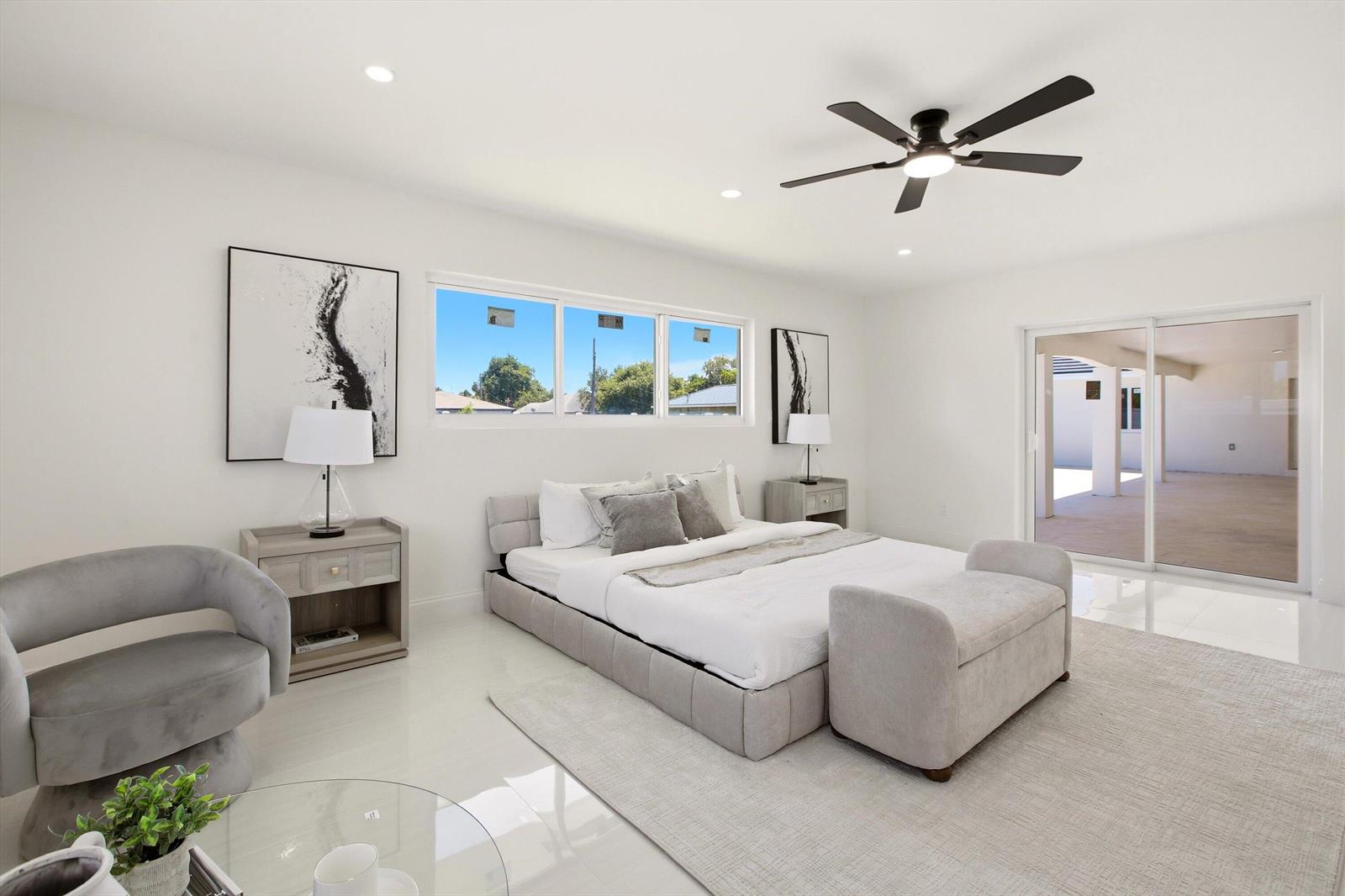 A modern bedroom features a platform bed, gray upholstered furniture, and a sliding glass door — 401 NW 3rd Place, Dania Beach FL 33004, DANIA BEACH, FL