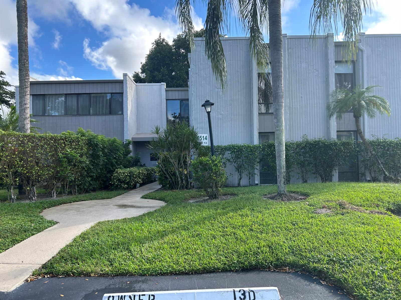 A two-story building with gray textured siding, palm trees, and a paved walkway — 6514 Spring Bottom Way # 125, Boca Raton FL 33433, BOCA RATON, FL