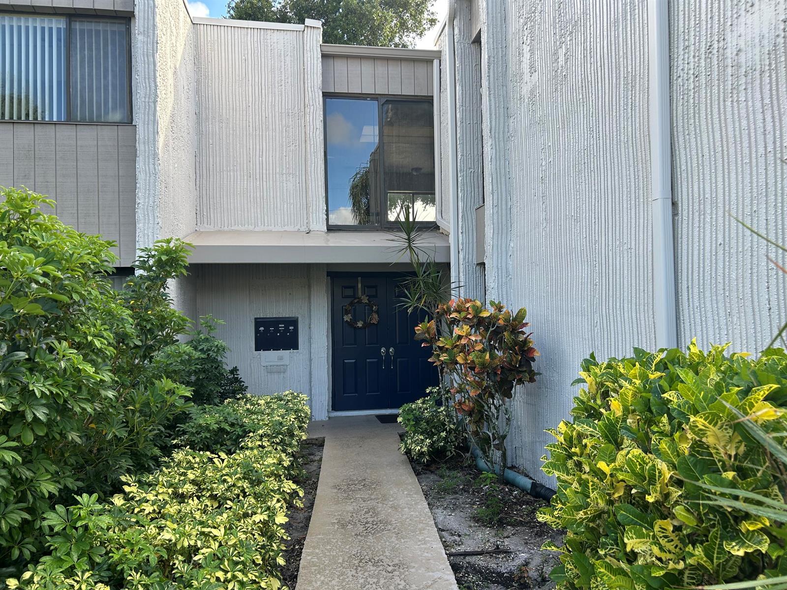 A concrete walkway leads to a dark blue double front door of a multi-story building — 6514 Spring Bottom Way # 125, Boca Raton FL 33433, BOCA RATON, FL