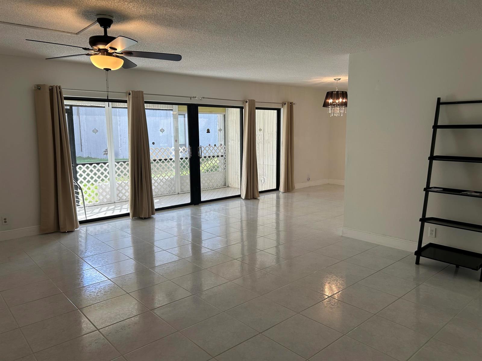 A spacious room with light tile flooring, a ceiling fan, sliding glass doors, and shelving — 6514 Spring Bottom Way # 125, Boca Raton FL 33433, BOCA RATON, FL