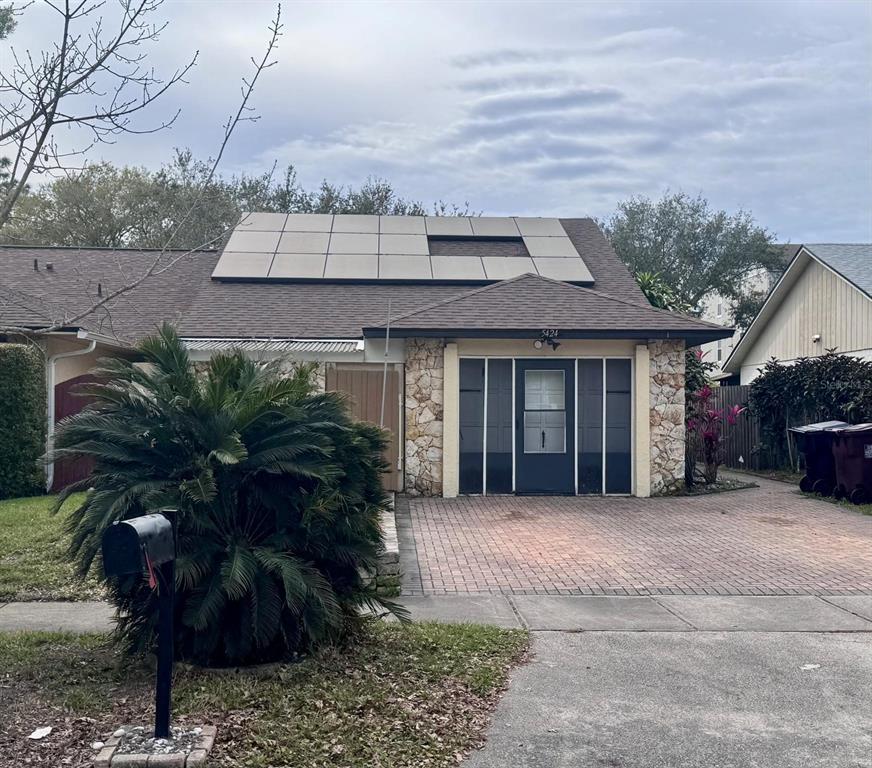 A single-story house with a stone facade, solar panels on the roof, and a driveway — 5424 SERENE LANE, ORLANDO, FL