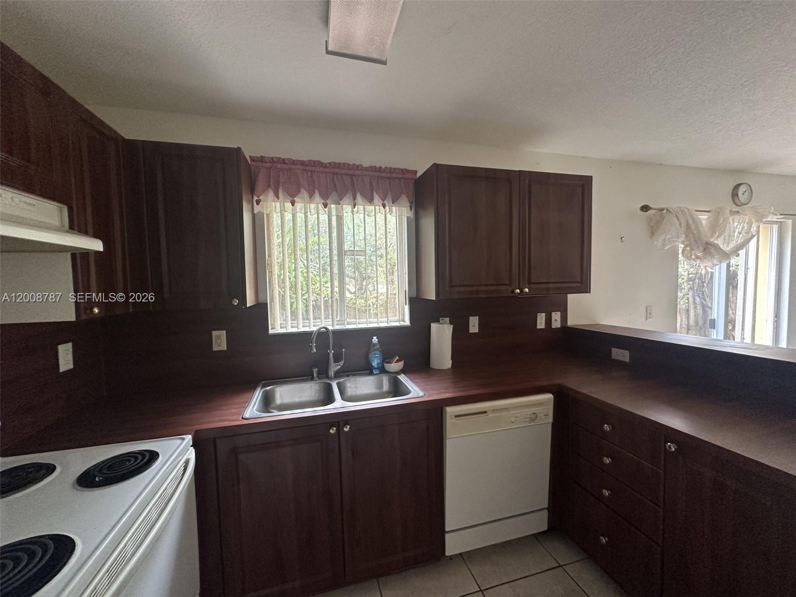 A kitchen features dark wood cabinets, a double-basin sink, and white appliances — 7125 NW 173rd Dr # 2401, Hialeah FL 33015, HIALEAH, FL