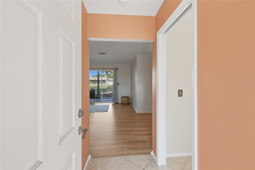 An entryway with tile flooring leads into a living area with wood-look floors and sliders — 404 OXFORD DRIVE UNIT 404, NOKOMIS, FL