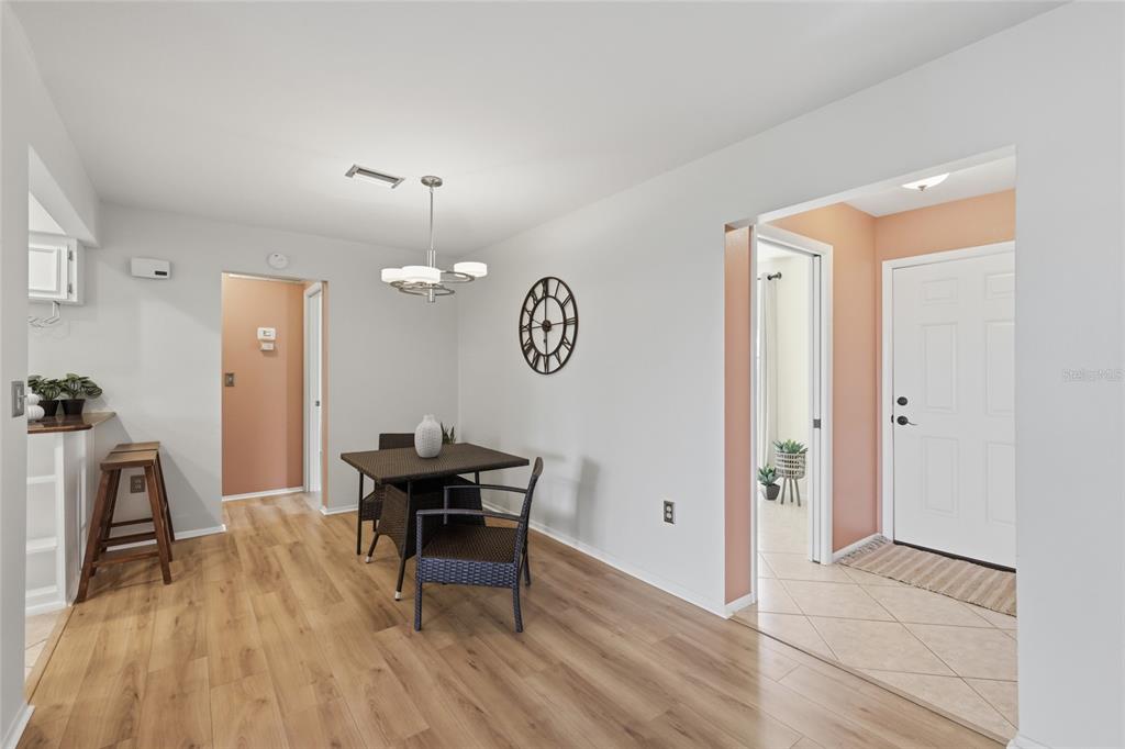 A dining area with wood-look flooring, a square table, and a modern light fixture — 404 OXFORD DRIVE UNIT 404, NOKOMIS, FL