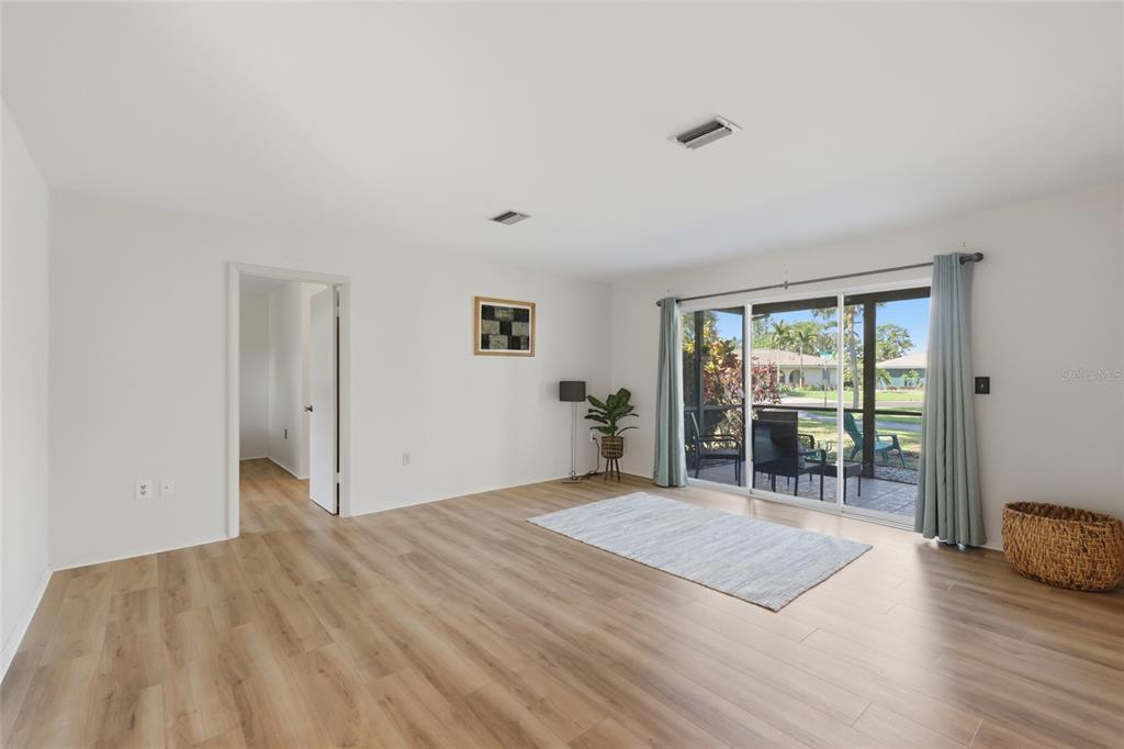 A living room with light wood-look flooring, white walls, and sliding glass doors to a patio — 404 OXFORD DRIVE UNIT 404, NOKOMIS, FL