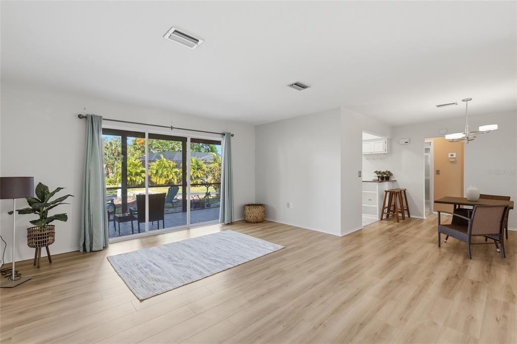 A bright living and dining area features light wood-look flooring and sliding glass patio doors — 404 OXFORD DRIVE UNIT 404, NOKOMIS, FL