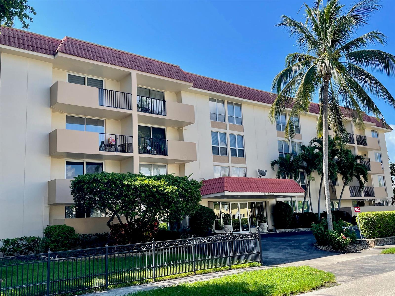 A multi-story apartment building with a red tile roof, balconies, and a palm tree — 1000 Spanish River Road # 2n, Boca Raton FL 33432, BOCA RATON, FL