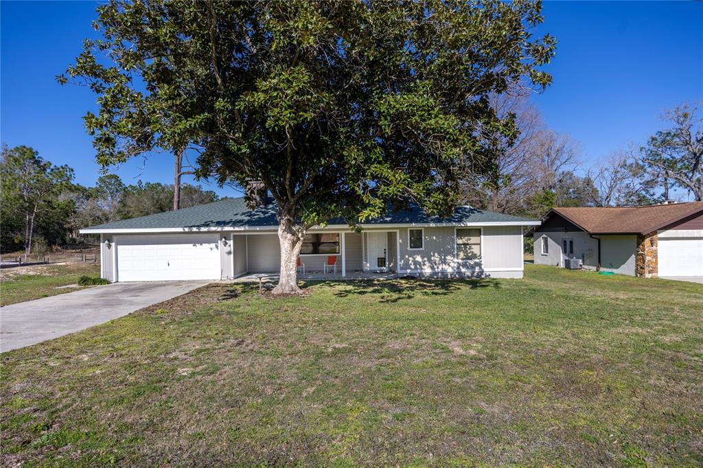 A single-story house with a gray exterior, a two-car garage, and a large front tree — 15181 NE 9TH STREET, WILLISTON, FL