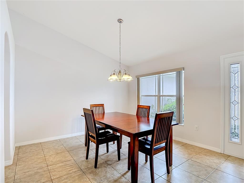 A dining room with a wooden table, four chairs, tile flooring, and a pendant light — 3490 DOW LANE, SPRING HILL, FL
