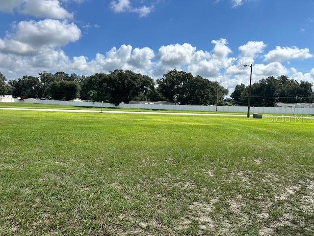 A large, grassy vacant lot under a blue sky with scattered clouds — 114 LAYNEWADE ROAD, POLK CITY, FL