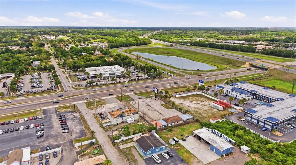 An aerial view shows a commercial area with parking lots, buildings, and a nearby highway — 8710 E COLONIAL DRIVE, ORLANDO, FL