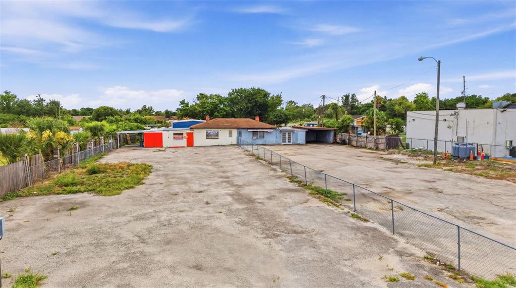 A wide, paved lot leads to a single-story commercial building with a fenced perimeter — 8710 E COLONIAL DRIVE, ORLANDO, FL