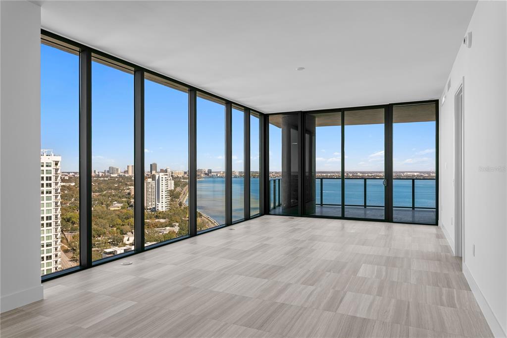 An empty room with floor-to-ceiling windows, light wood-look flooring, and a view of water — 3015 S YSABELLA AVENUE UNIT 2301, TAMPA, FL