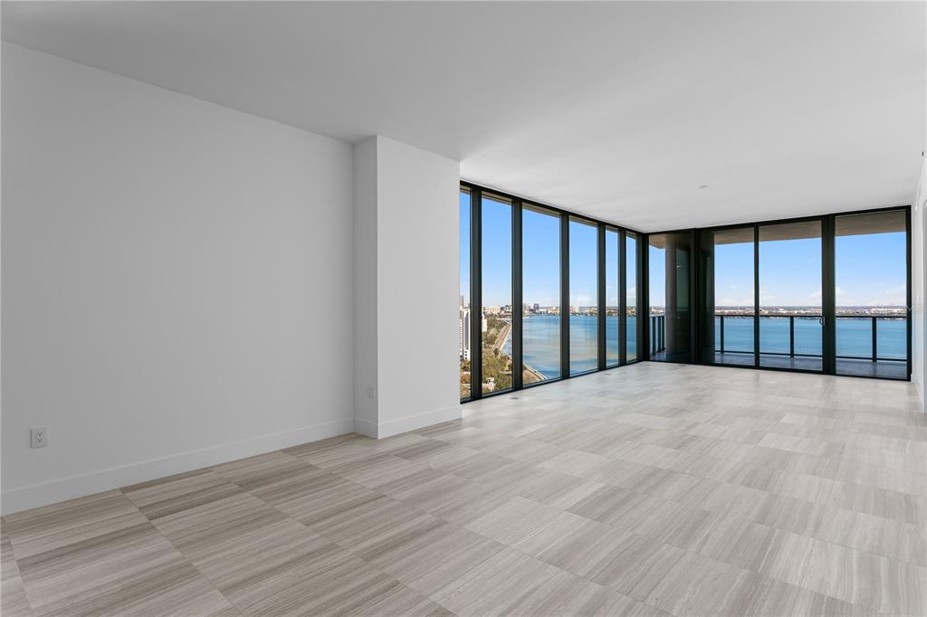 An empty room with light-colored tile flooring and floor-to-ceiling windows overlooking a bay — 3015 S YSABELLA AVENUE UNIT 2301, TAMPA, FL