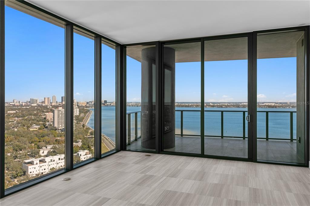A modern room with floor-to-ceiling windows, light wood-look tile floors, and a balcony overlooking water — 3015 S YSABELLA AVENUE UNIT 2301, TAMPA, FL