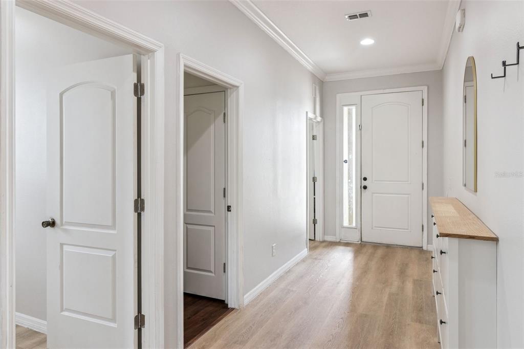 A bright entryway features light wood-look flooring, white walls, and several interior doors — 647 CHICAGO WAY, DUNDEE, FL