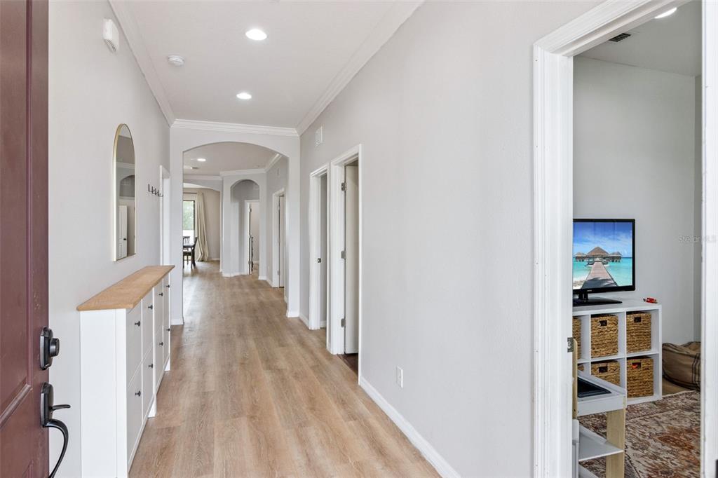A hallway with light wood-look flooring leads to an arched opening, with a side room visible — 647 CHICAGO WAY, DUNDEE, FL