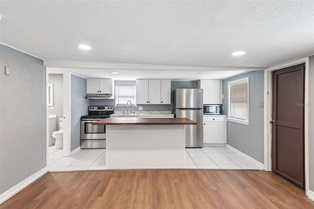 A kitchen features white cabinets, stainless steel appliances, a wood-topped island, and tile flooring — 37732 CECIL LANE, ZEPHYRHILLS, FL