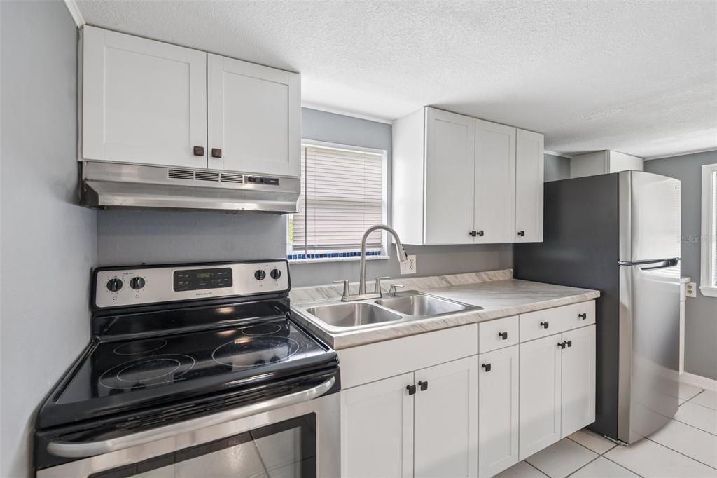 A kitchen features white cabinets, stainless steel appliances, a double sink, and light-colored countertops — 37732 CECIL LANE, ZEPHYRHILLS, FL