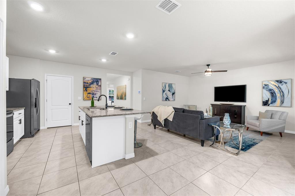An open-concept kitchen and living room featuring tile floors, a center island, and neutral walls — 505 LADY IRELYN COURT, DELAND, FL