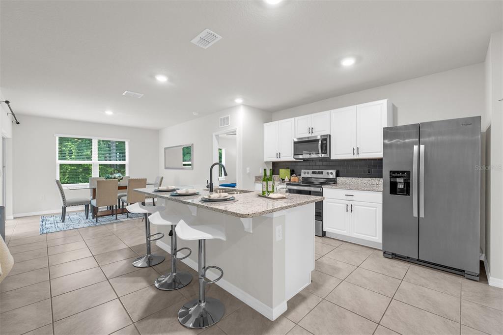 A kitchen with white cabinets, granite countertops, stainless steel appliances, and a central island — 505 LADY IRELYN COURT, DELAND, FL