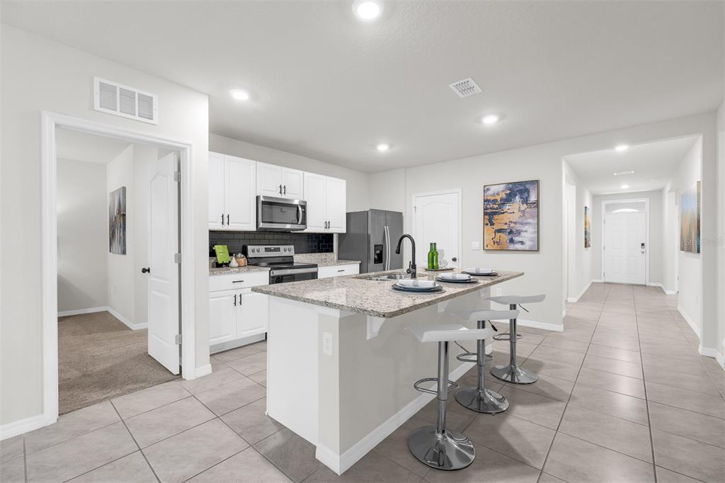 A modern kitchen features white cabinets, granite countertops, a center island, and tile flooring — 505 LADY IRELYN COURT, DELAND, FL
