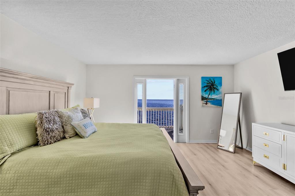 A bedroom features a light green bedspread, a white dresser, and a balcony overlooking water — 5026 COQUINA KEY DRIVE SE UNIT 5026, ST PETERSBURG, FL