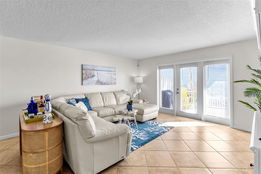 A living room features a white sectional sofa, a blue area rug, and glass patio doors — 5026 COQUINA KEY DRIVE SE UNIT 5026, ST PETERSBURG, FL
