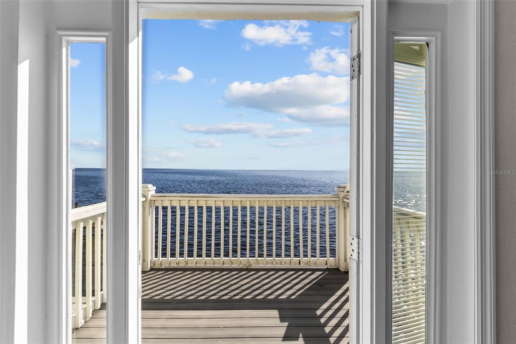 A doorway opens onto a wooden deck overlooking the ocean under a blue sky — 5026 COQUINA KEY DRIVE SE UNIT 5026, ST PETERSBURG, FL