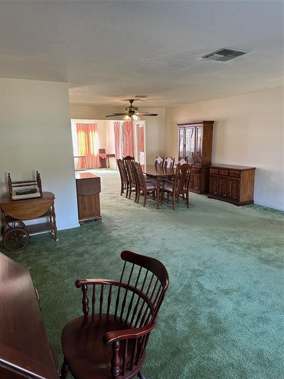 A dining area with a wooden table and chairs sits on green carpeted flooring — 200 S DESOTO STREET, BEVERLY HILLS, FL