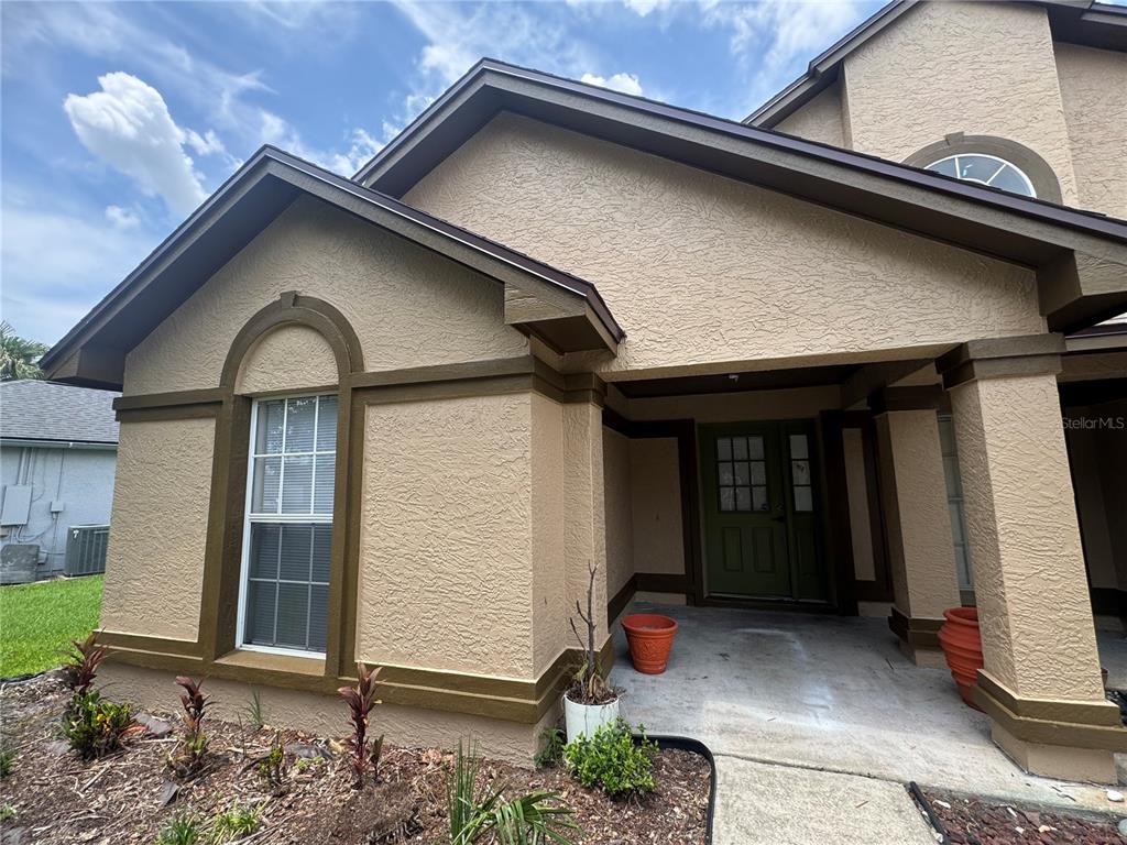 The exterior of a tan stucco house features a covered entryway and a front window — 11128 SYLVAN POND CIRCLE, ORLANDO, FL